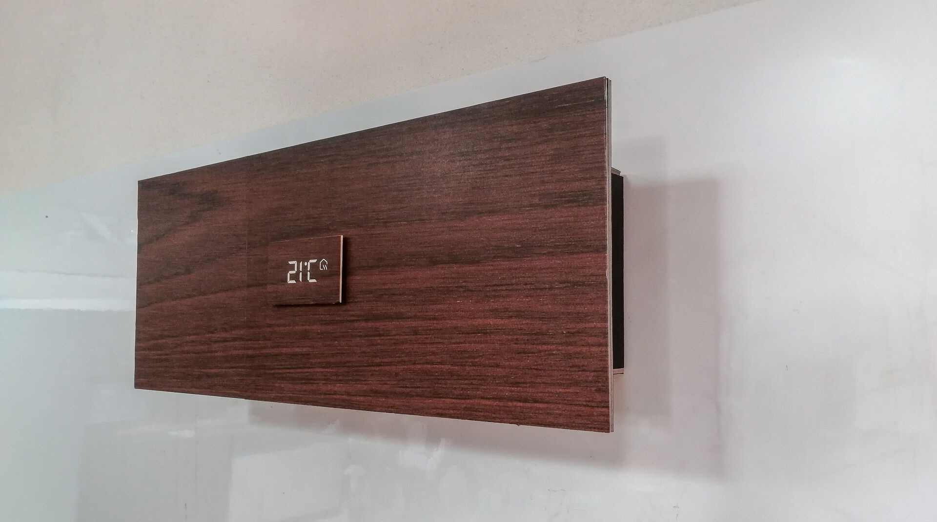 Prototype mural de la Solar Box Air Booster avec façade en bois foncé et affichage numérique de la température